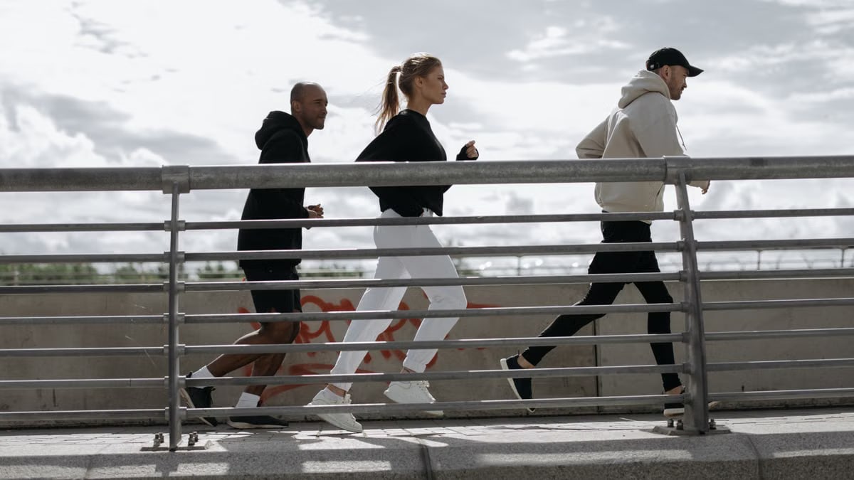 Three people jogging on a bridge, representing a healthy lifestyle outdoors.